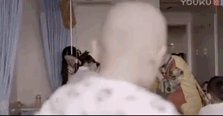 在病房里,一个医生扮成小丑的样子,逗生病的孩子开心,输着液