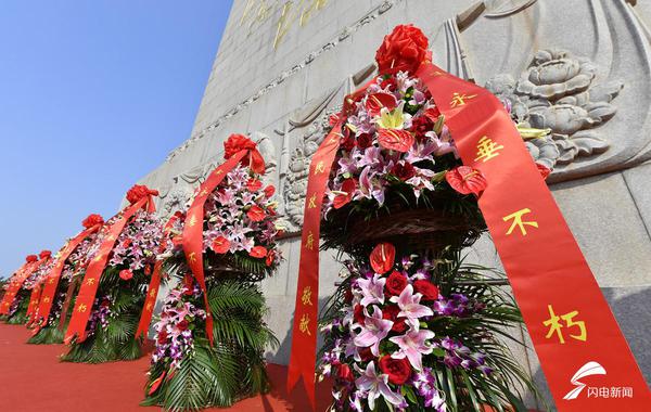 巍然矗立的革命烈士纪念塔前,11个大型花篮一字排开,花篮的红色缎带上