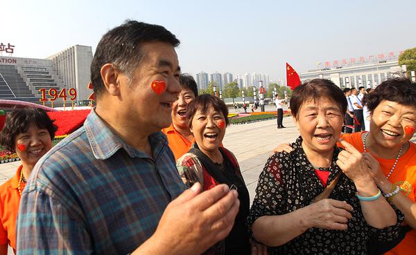 一群大叔大妈为了加入祝福祖国的快闪活动,高兴地将五星红旗贴在脸上.